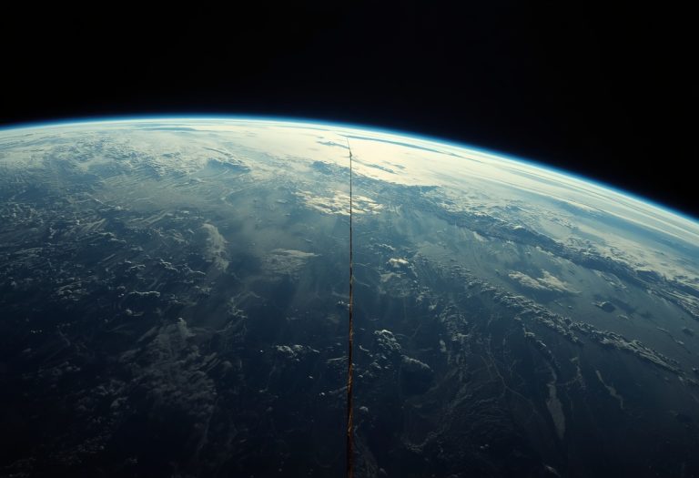 Sandra Bullock in a spacesuit floating in orbit above Earth with debris and spacecraft visible in the darkness of space.