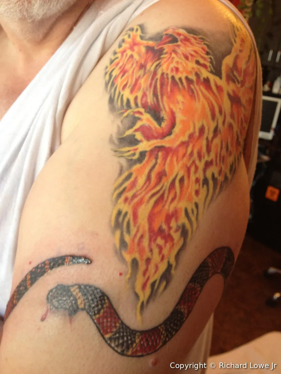 Richard Lowe's freshly inked phoenix tattoo in red, orange and yellow flames on his upper arm, with a coral snake band below it