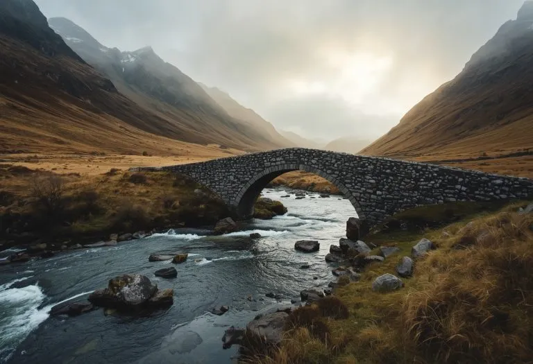 The stone bridge at Sligachan on the Isle of Skye crosses a river with mountains in the background. TITLE: Sligachan Bridge